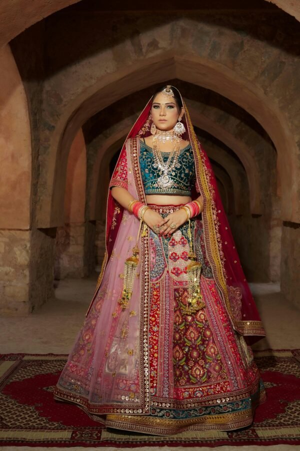 bride standing in green and reddish-pink lehenga.