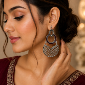 Woman wearing oxidized statement earrings with maroon accent and intricate drop design