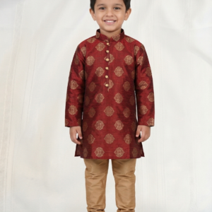 Young boy wearing maroon kurta with gold motifs and beige pajama pants